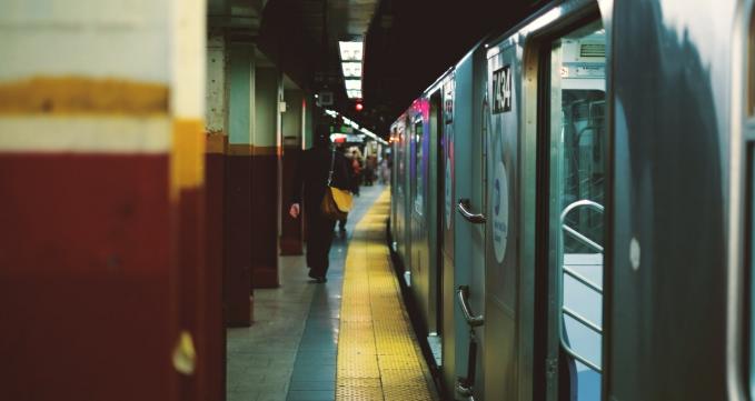 Narrow walkway between subway train on the right and pillars on the left.