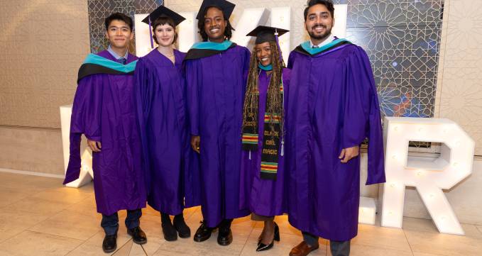 group of students in purple graduation regalia smiling for camera