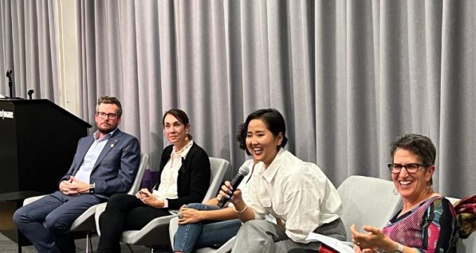 Handaa Enkh-Amgalan, in a white blouse, laughing with a microphone in her hand while interacting with the students. Other panelists smiling as well. 