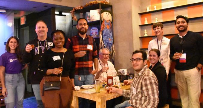 A group of alumni posing for a photo around a table