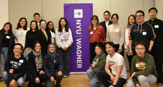 Attendees posing in front of the NYU Wagner banner for a group picture